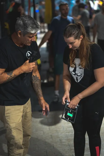 A participant squeezes the dynamometer while the host checks the reading.