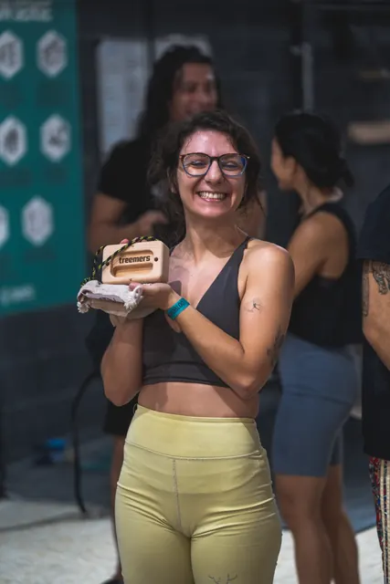 A winner smiling with her wooden prize.