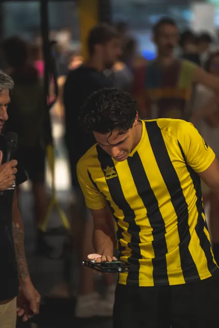 A judge in a yellow striped shirt keeps time on a tablet.
