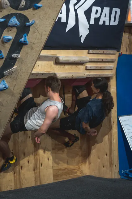 Two people hanging in a kneebar under the Black Pad banner.
